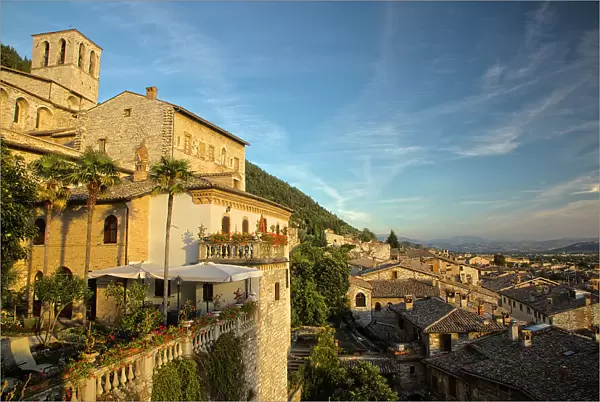 Italy, Umbria. Evening light on flower covered buildings overlooking the medieval town of Gubbio