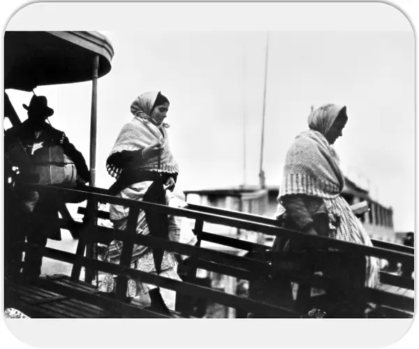 ELLIS ISLAND: IMMIGRANTS. Immigrants walking down the gangplank from a ferry boat at Ellis Island