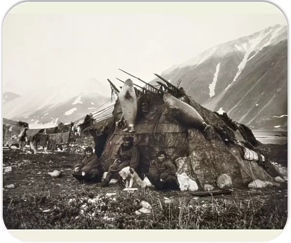 ESKIMO DWELLING, c1899. A group of three Inuits sitting in front of their house