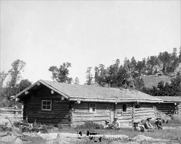 SOUTH DAKOTA: LOG CABIN. Five men sitting in the grass in front of an old log cabin