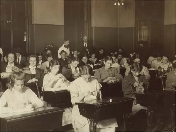 DRESSMAKING CLASS, 1909. Working girls learning dressmaking in a free evening class