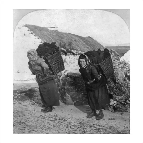 IRELAND: PEAT FUEL, c1903. Women carrying peat for fuel in the village of Dooagh on Achill Island