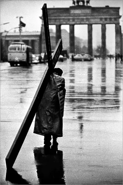 BERLIN: MAN AND CROSS, 1961. A man carrying a cross on a street in West Berlin