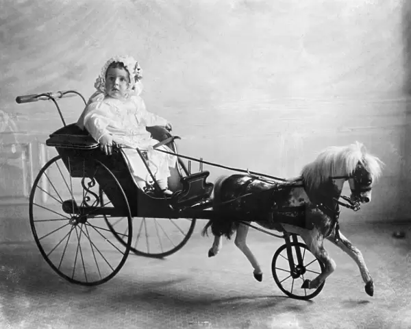 Vinson Walsh McLean, son of American heiress and socialite Evalyn McLean, sitting in a toy horse and carriage. Photograph, 1911