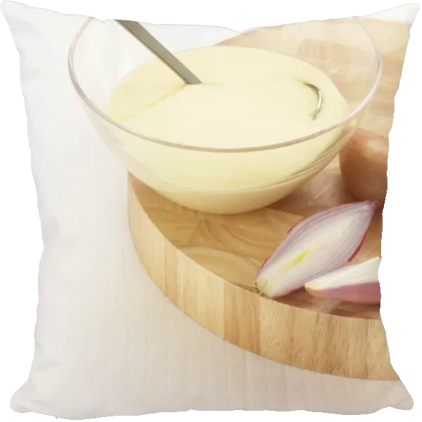 Beurre Blanc, traditional French sauce made with white wine, butter and shallots, fresh shallots nearby, on chopping board, close-up