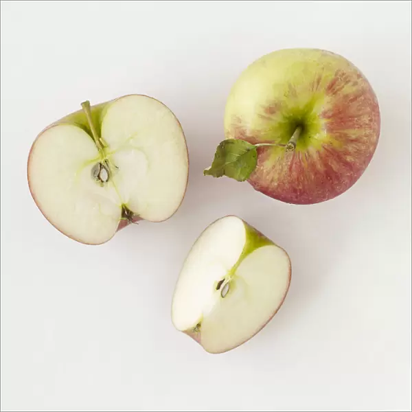 Whole apple, halved apple, and apple slice, close-up