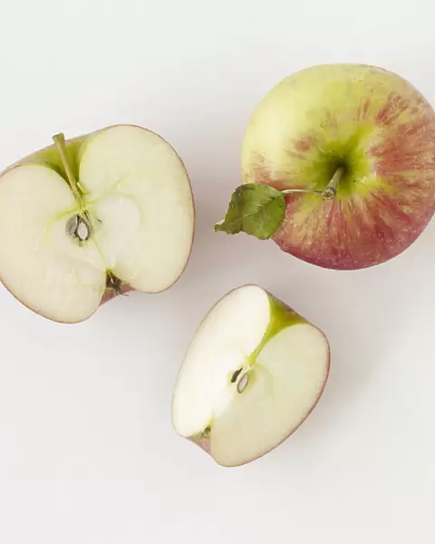 Whole apple, halved apple, and apple slice, close-up