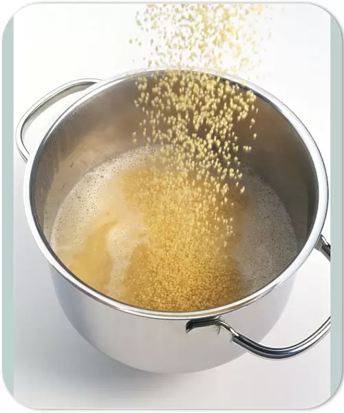 Couscous being poured into boiling water in a saucepan