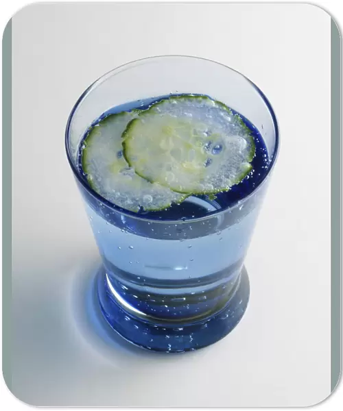 A glass of water garnished with thin slices of lime, high angle view