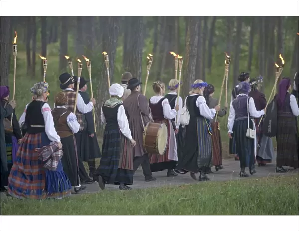 Lithuania, Klaipeda County, Curonian Spit, Nida, Torch lit procession of people wearing traditional clothing