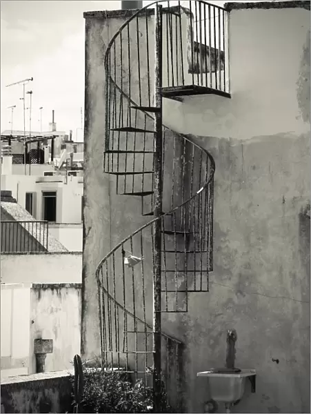 Old cast iron spiral staircase accessing a rooftop terrace in Otranto, Apulia, Italy