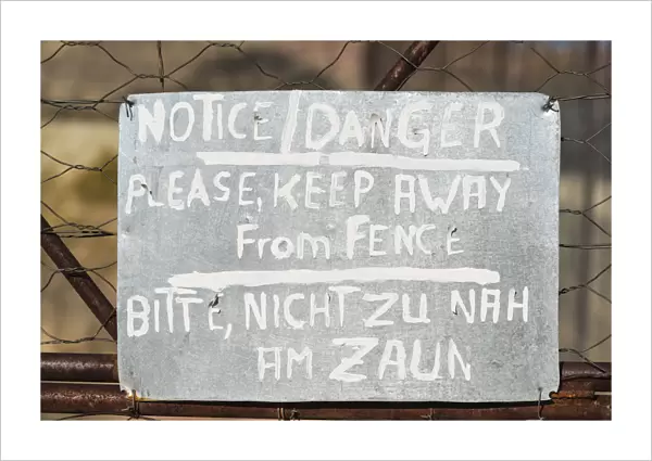 Warning sign in English and German on the fence of a predator enclosure, Namibia