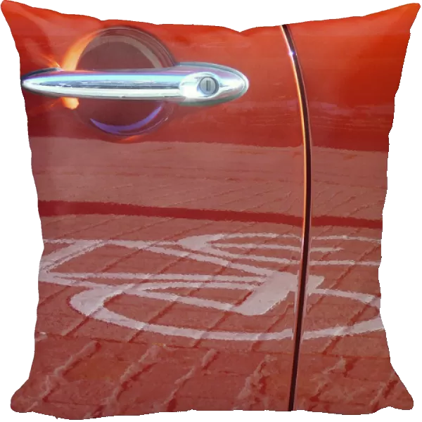 Red car door reflecting a pictogram from a bicycle lane
