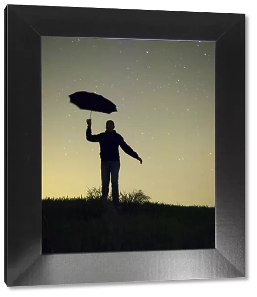 Silhouette of a man with an umbrella in the night