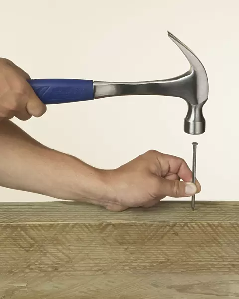 Person hitting nail into wood with hammer