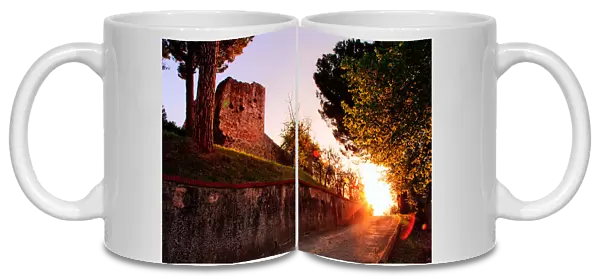 Fortress. Sun sets down road leading castle on hilltop fortress of San