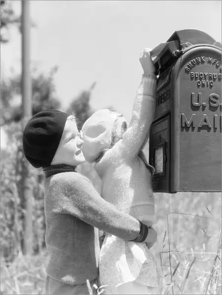Boy lifting up girl to reach U. S. mail box, helping her mail letter