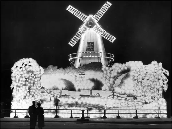Well Lit. Visitors admiring the windmill, one of the illuminations at Blackpool