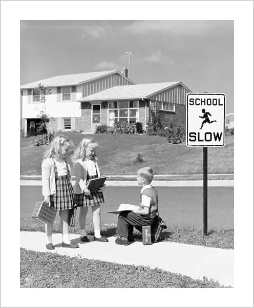 Two girls walking to school, boy sitting on lunchbox. (Photo by H