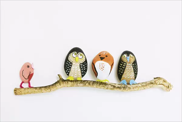 Decorated painted stone birds perching on a branch