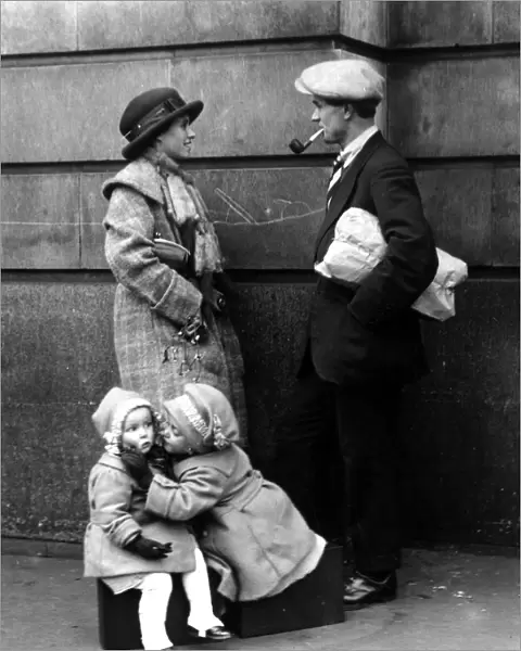A couple chatting while their children are kissing under the mistletoe 25 December 1921