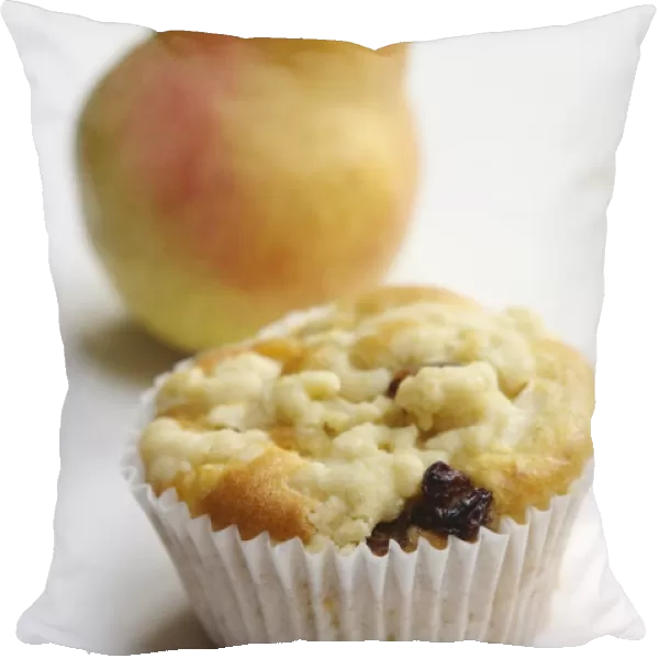 Raisin muffin in plain paper case, topped with grated pear and with whole pear behind
