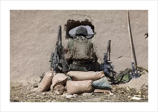 A U. S. Marine sniper observes his sector at a patrol base near Sangin, Afghanistan