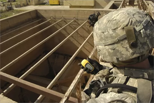 U. S. Army soldier takes a GPS grid reading at a water treatment plant