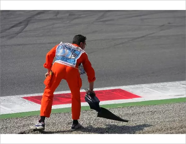 Formula One World Championship: A marshal collects a bit of broken body work from the first chicane