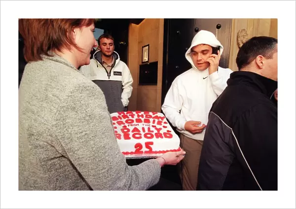 Robbie Williams gets a 25th birthday cake from Margaret Mallon February 1999 as he walks
