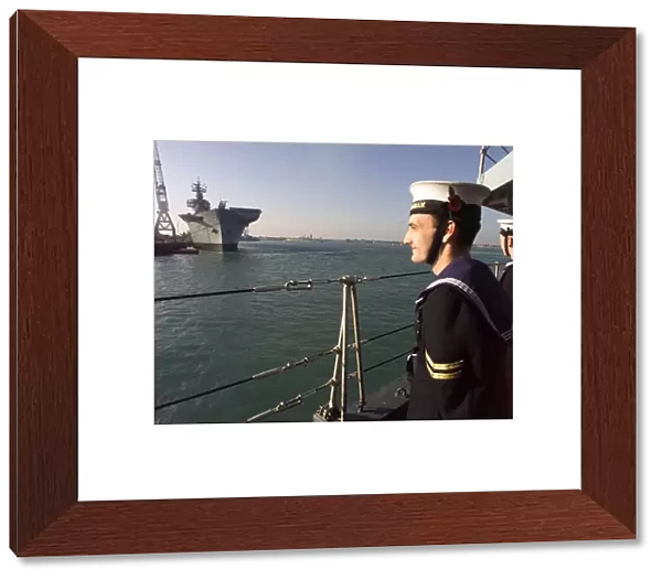A sailor from HMS Birmingham stands to attention as the ship passes HMS Ark Royal in