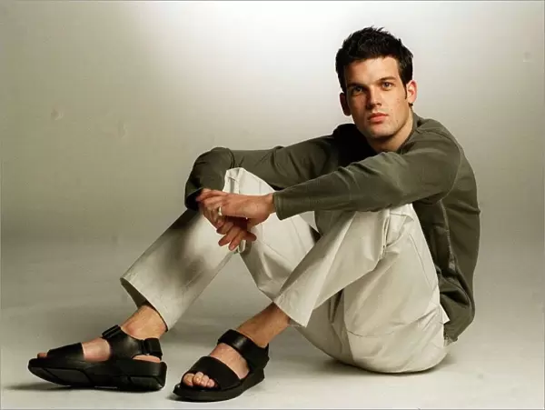 Adam Sinclair actor in studio January 1999 wearing green jumper cream trousers sandals