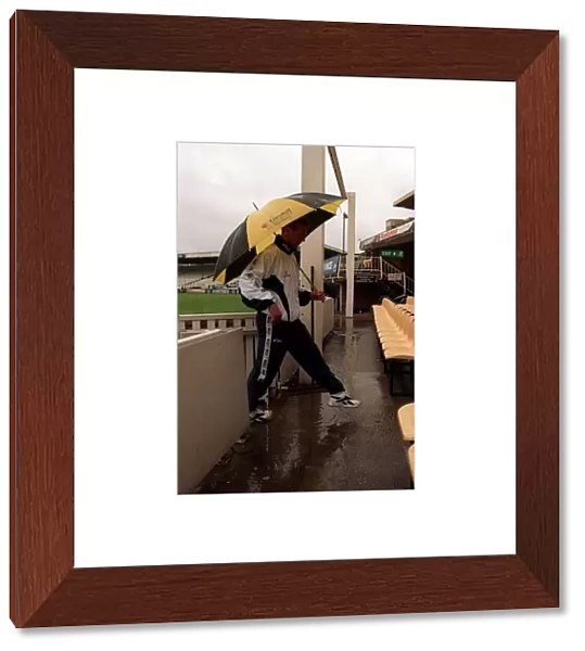 Alec Stewart England Cricket Captain June 1998 walks under an umbrella at
