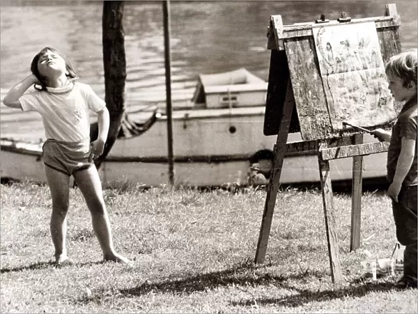 Little girl is posing whilst the young painter gets to work. Circa 1960