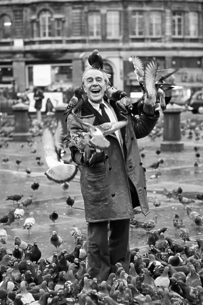 Comedian Max Wall poses in trafalgar Square, London, with seagulls flying on to his head