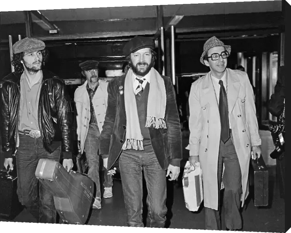 Eric Clapton (centre in beret) pictured leaving Heathrow airport for California