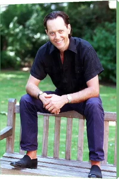 Richard E Grant sitting on a bench August 1998 SOON TO APPEAR IN BBC TVs