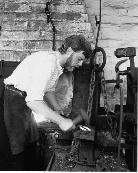 Blacksmith in his forge, working on a horseshoe