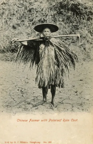 Chinese Farmer with Palmleaf Raincoat carrying hoe