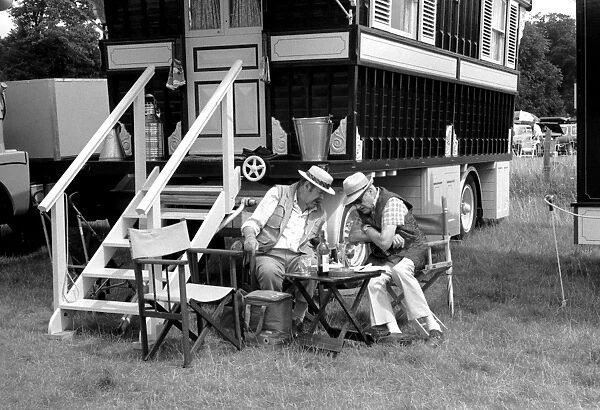 Two men sitting outside a caravan