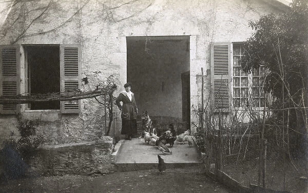 Woman with a dog and chickens in a garden, France