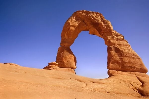 Delicate Arch - delicately sculptured sandstone arch standing on a slickrock slope. In late evening - Arches National Park, Utah, USA