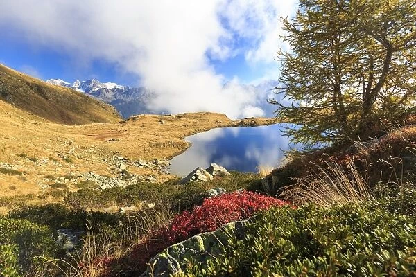 Clouds on peaks of Bernina Group reflected in Lake Arcoglio, Val Torreggio, Malenco Valley