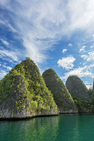 A view of islets covered in vegetation from inside the natural protected harbor in Wayag Bay, Raja Ampat, Indonesia, Southeast Asia, Asia