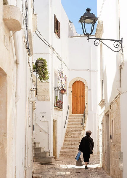 Woman walking in a narrow street in the Old Town, Locorotondu, Puglia, Italy, Europe