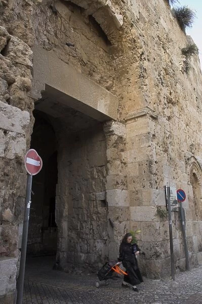 Woman walking out of old city through Zion Gate