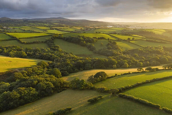 Aerial vista over farmland in evening sunshine, Devon, England. Summer (August) 2019