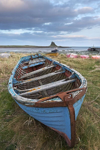 Old fishing boat pulled up on the shore at Holy Island, with the castle across the bay