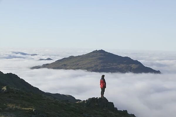 A women walker looking towards Harter Fell in the Lake district above the cloud