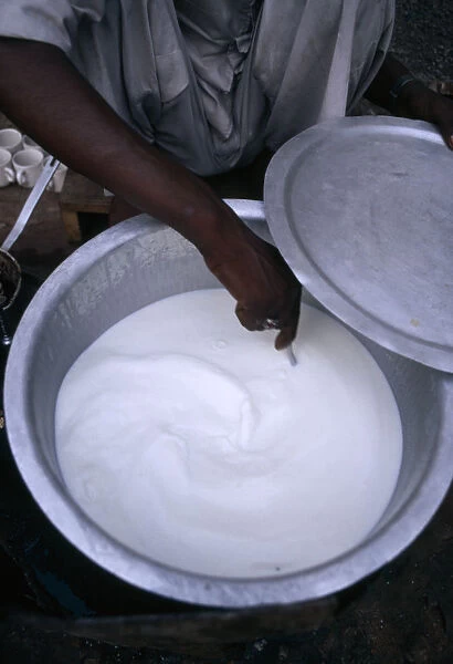 10067277. INDIA Varanasi Hand stirring yogurt being mage in aluminium bowl